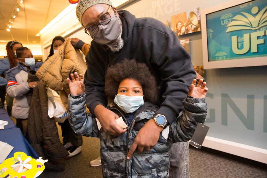 UFT District 9 Representative Aqeel Williams helps a boy try on his new coat. 