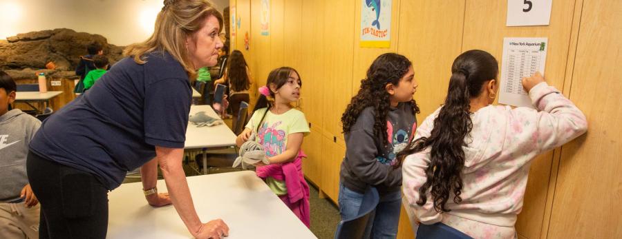 Teacher Maureen Collins watches as her 3rd-graders track the route their tagged "sharks" took.