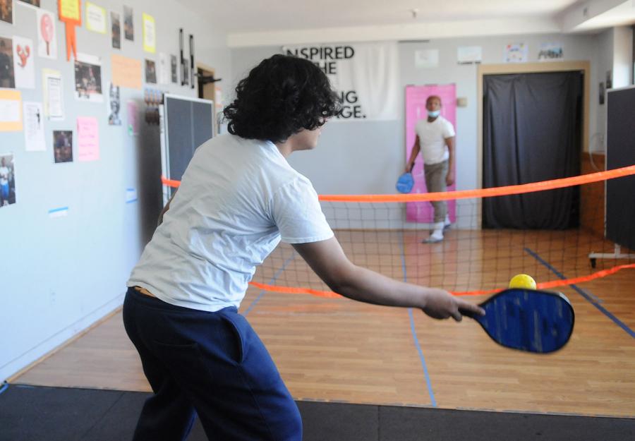 From their classroom windows, the students of St. John’s Residence for Boys in Queens can see the rich recreational landscape of the Rockaways — the ocean, the boardwalk, volleyball and basketball courts, roller rinks — a landscape they aren’t permitted to experience. When the boys spotted a pickleball court from the window and asked what it was, veteran physical education and Spanish teacher Jenine DeMarzo (inset) decided to set up a makeshift pickleball net in her classroom to introduce them to the game. 
