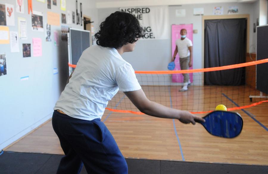 From their classroom windows, the students of St. John’s Residence for Boys in Queens can see the rich recreational landscape of the Rockaways — the ocean, the boardwalk, volleyball and basketball courts, roller rinks — a landscape they aren’t permitted to experience. When the boys spotted a pickleball court from the window and asked what it was, veteran physical education and Spanish teacher Jenine DeMarzo (inset) decided to set up a makeshift pickleball net in her classroom to introduce them to the game. 