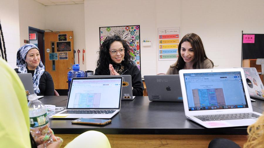 Female Teachers sitting at table collaborating with laptops