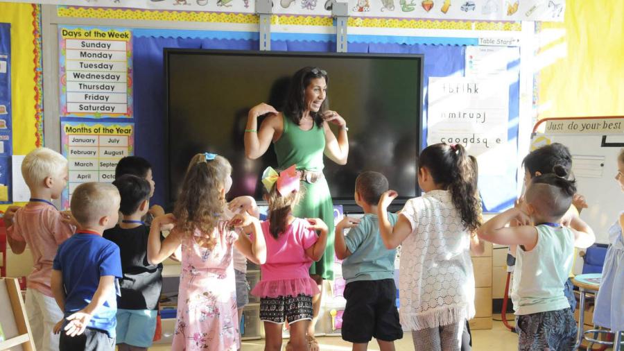 UFT teacher standing with hands on shoulders in classroom in front of kindergarten students