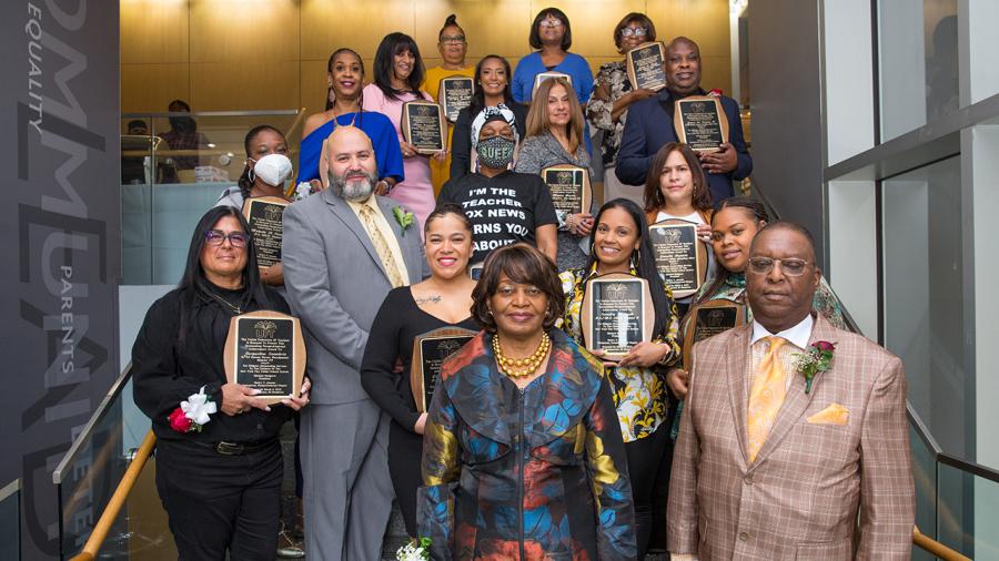 Awardees pose on a stairwell holding up their plaques
