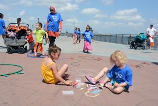 Those two young to run stay busy drawing with chalk, while others jump rope.