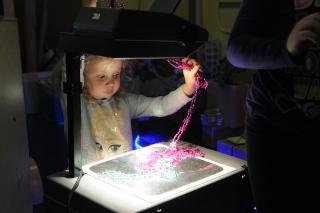 A student arranges jewelry on the projector to create an interesting image.