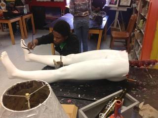 A student transforms a discarded mannequin into a floor lamp.