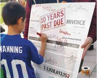 A young student in Peekskill signs his name to an invoice showing the $3.9 billi