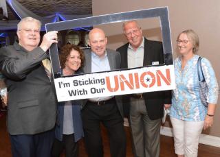 People pose behind cutout that says, "I'm sticking with our Union"