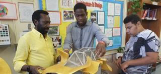 Teacher Yvon Milien (left), with two students, lowers the gallery roof.