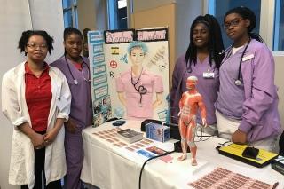 Students, teacher stand behind a medical display