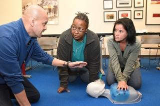Parents Jennifer Sayers (center) and Annette Rodriguez learn CPR skills during a