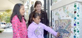 A 4th-grader and 2nd-grader survey their mosaic with Evelyn Ortiz, the chapter leader and arts coordinator at PS 159, at the opening day ceremonies at the Morrisania park on Sept. 17. 