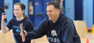 Scholars Academy athletic director Joe Lunati guides an 8th-grader to proper for