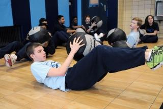 An 8th-grader uses a medicine ball at the Russian Twist station.
