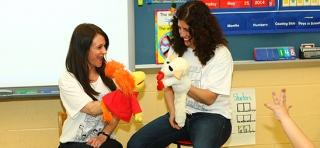 Michelle Sharabi and Hope Fogarty use puppets to teach kindergarten students about resolving conflicts. 