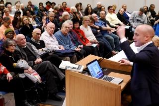 Man stands in front of a seated crowd