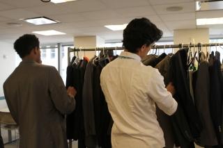 Boys browse racks of dress suits.