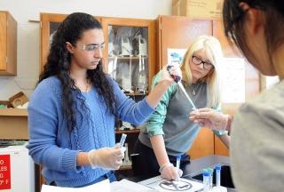 Twelfth-graders use a micropipette to measure out a sample.