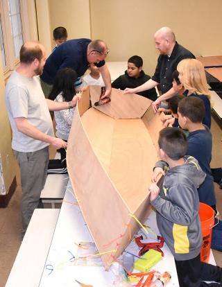 It's all hands on deck as project director Heinz drills holes to attach the boat