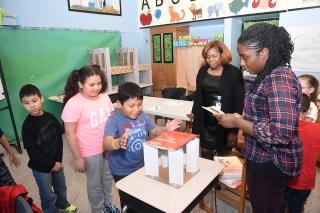 A 3rd-grader tests out the weight-bearing strength of a triangular column under 