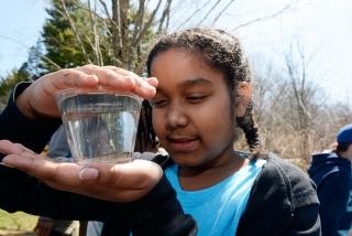 Rebekah is careful when handling the trout in a cup.