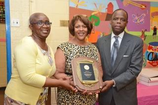 Harrison (center), flanked by Brown (left) and Principal Collin Wolfe, receives 