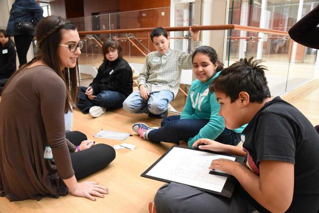 Teacher Liana Rosenman watches as students work together to match their shapes t