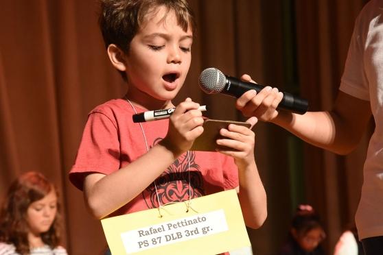A 3rd-grader repeats a word and writes it on his slate.