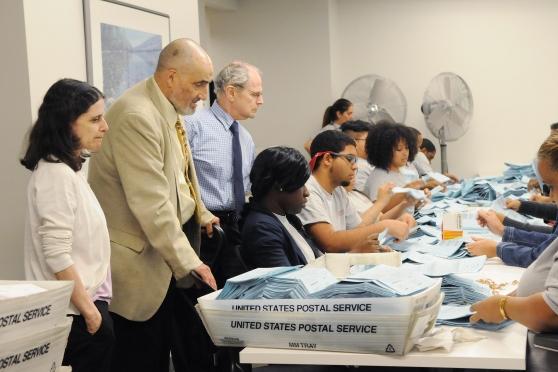 Caucus representatives watch the vote count at American Arbitration Association 