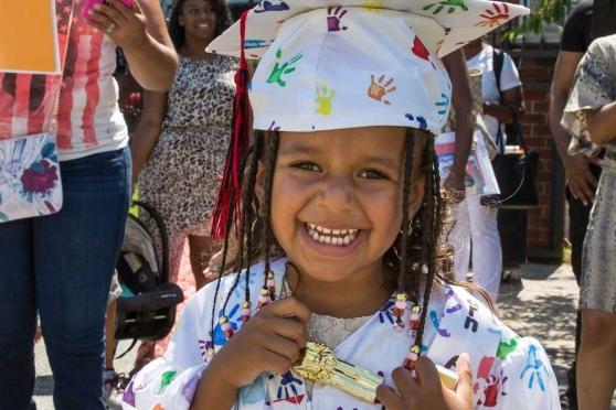 Wearing a custom-made cap and gown, one of four youngsters who “graduated” clutc
