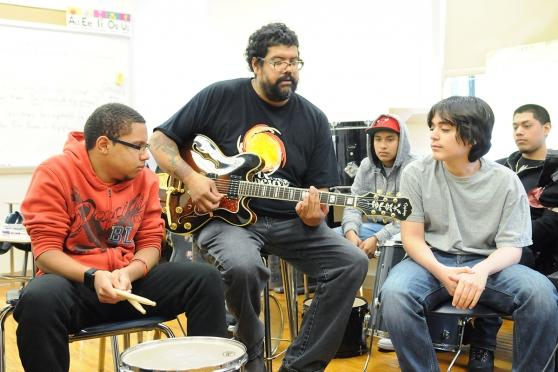Rosello, here leading band practice, uses music and theater to help keep students focused.