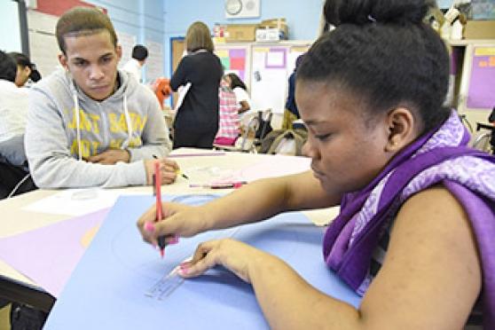 Two seniors in Uy’s geometry class work to construct Apollonian gaskets, fractal patterns generated from triples of circles.