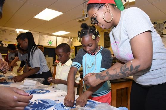 Brown helps a youngster from PS 5 make a snowflake during a mentoring program at