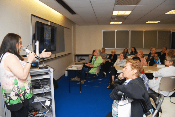 Speaker at a mike in a room full of classroom attendees