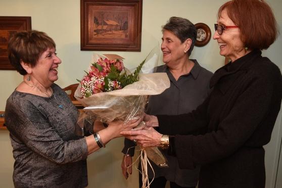 Vera Stasny (right) presents flowers to hostess Reichert as Joan Derwin looks on