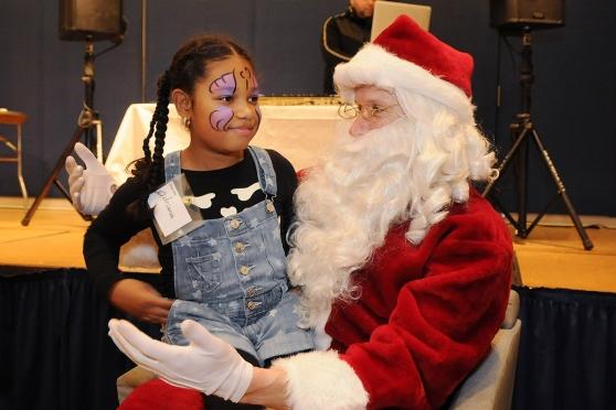 A youngster and Santa Claus share a private conversation. 