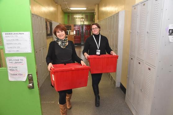 Librarians Susan Westover (left) and Amanda Clarke deliver the big, red bins to 