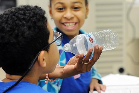Sixth-graders test out their theory of air pressure.