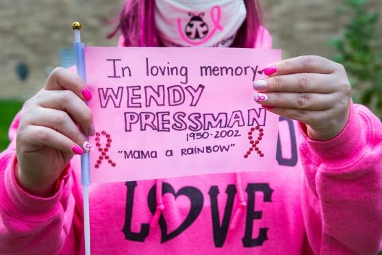a woman holds up a sign honoring her late mother