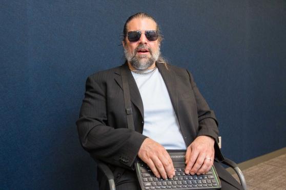 A blind man sits and types on a keyboard 