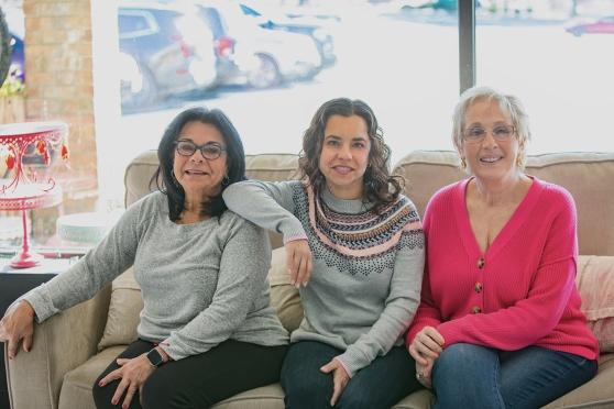 Three women pose on a couch