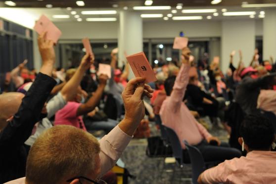 People raising hands with ballots