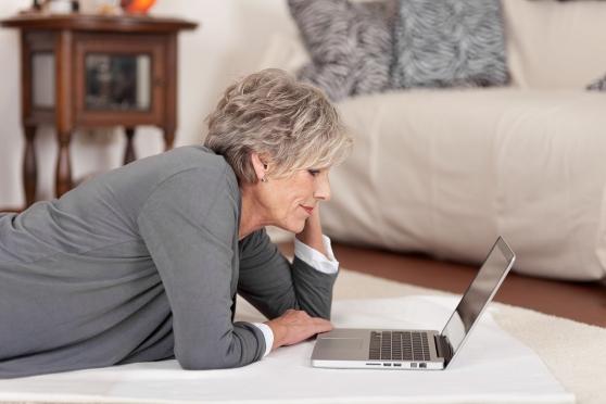 Mature woman laying on the floor looking at her laptop
