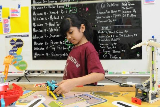A student works with her robotics team’s LEGO robot.