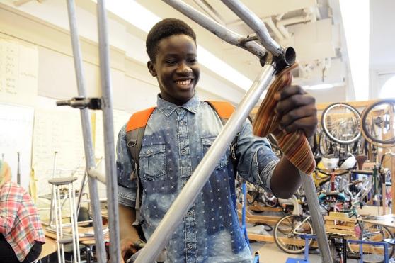 Modou Fall cleans the frame of a bicycle he’s reconditioning as part of the Earn