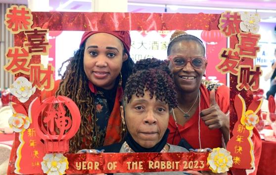 Three women pose for a photo in a Lunar New Year themed frame 