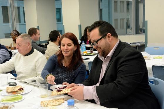 A woman spreads horseradish on a man's matzoh