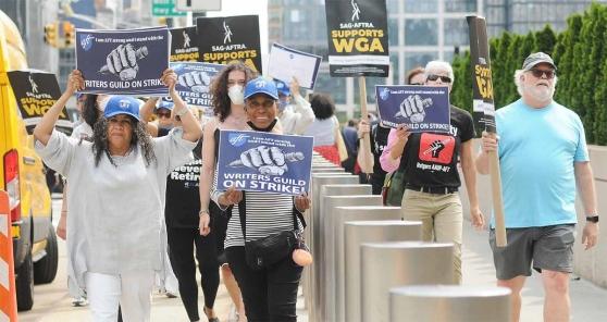 A group of members hold signs in support of the WGA