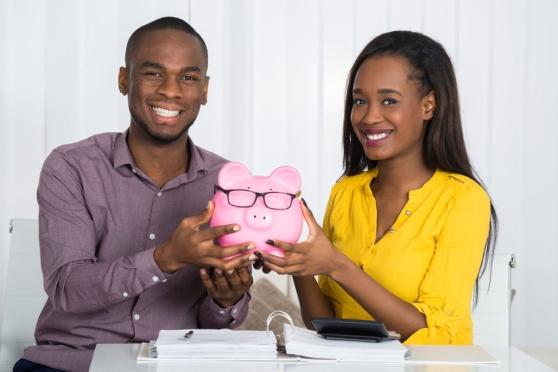 A man and a woman hold up a piggy bank