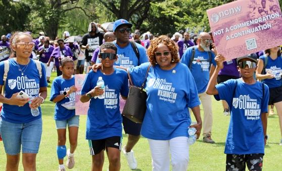 A group of people holding signs walk in a march 